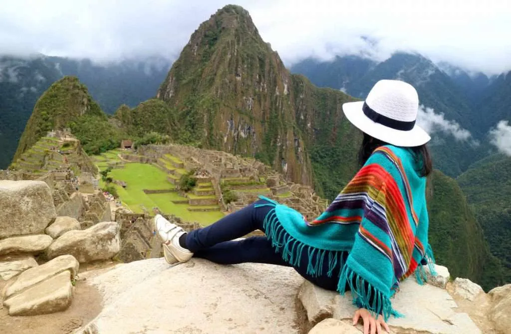 Young female traveler admiring the Inca ruins of Machu Picchu