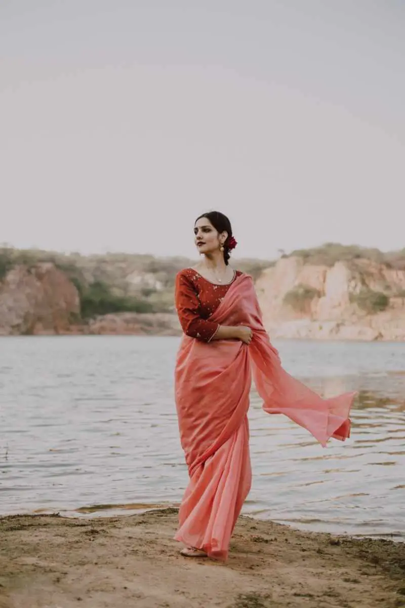 Elegant ethnic woman wearing silk sari standing on river shore