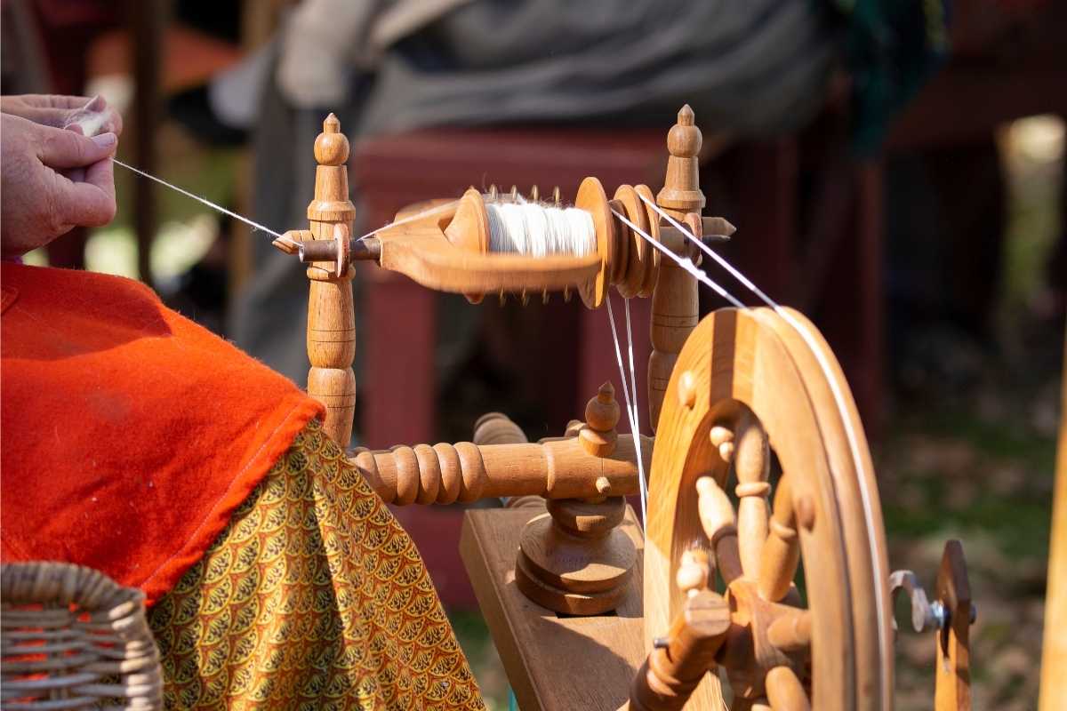 Female artisan spins yarn with spinning wheel