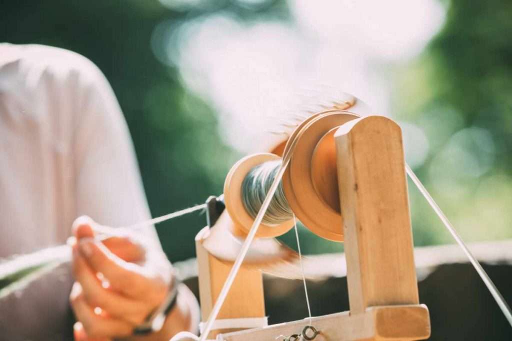 Young-Woman-Using-A-Spinning-Wheel-To-Spin-Wool
